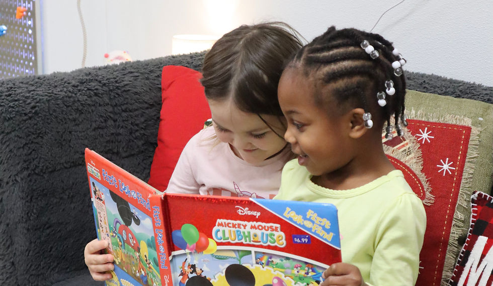 Two toddlers reading a book together on the classroom couch at Everstar Academy