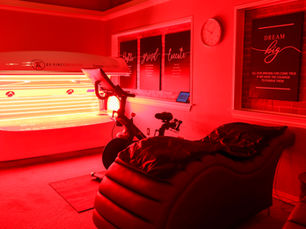 A room with a red light therapy bed, the oxygen therapy bike and the PEMF lounge chair.
