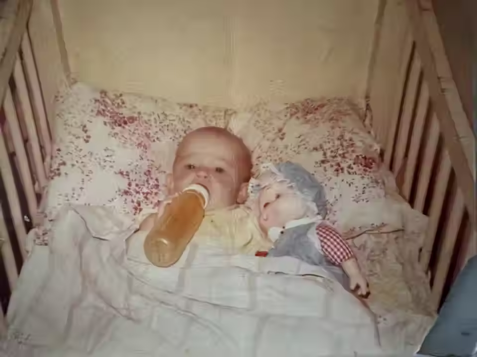 Jessica Gaudie as a baby in her crib drinking a bottle.