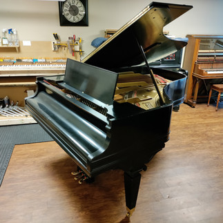 A black Knabe grand piano in a workshop