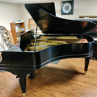 A black Knabe grand piano in a workshop