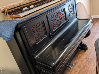 A black Mason and Hamlin upright with a grand piano action laying on top