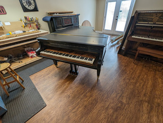 A black Knabe grand piano inside a piano workshop