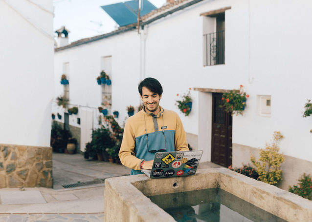 Remote worker using laptop by fountain at Rooral rural coliving space in Spain, ideal for digital nomads and remote workers
