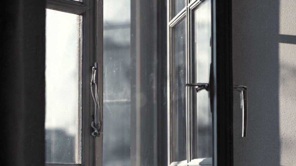 Open window with sunlight streaming in, illuminating a white wall. The scene is tranquil with a cool, muted color palette.