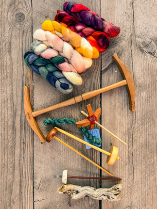 Colorful wool braids of roving and wooden spinning tools on rustic wooden boards. Earthy tones, vibrant yarns create a warm, creative ambiance.