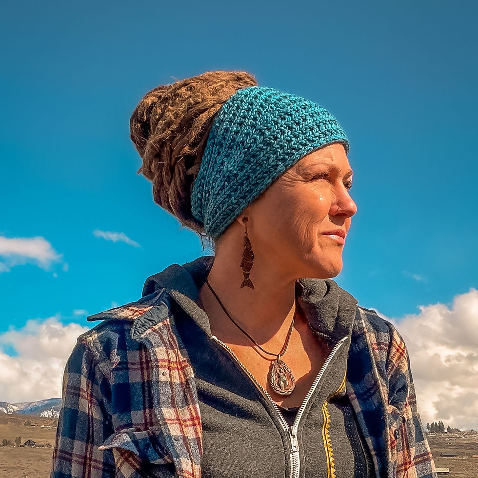 A person wearing a blue headband knitting pattern piece in a broken rib stitch, looking to the side outdoors.