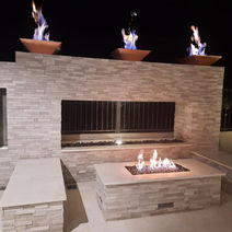 Night view of three fire features with surrounding seating area.