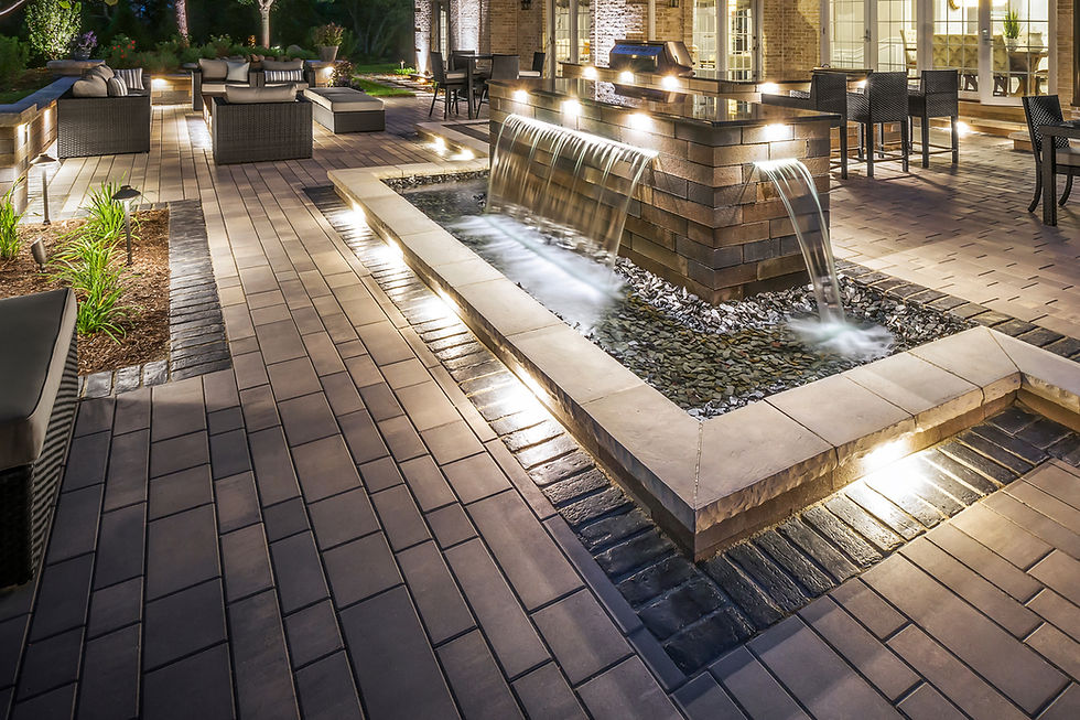 Modern outdoor living space featuring elegantly integrated lighting within the hardscape, beautifully illuminating the water feature and seating area.
