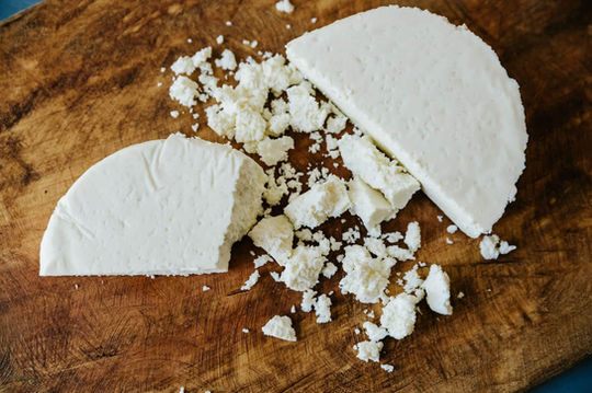 Queso fresco crumbled on wood cutting board