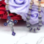 Elegant handmade amethyst rosary with silver accents, intricate beadwork, & a detailed purple crucifix, displayed on marble