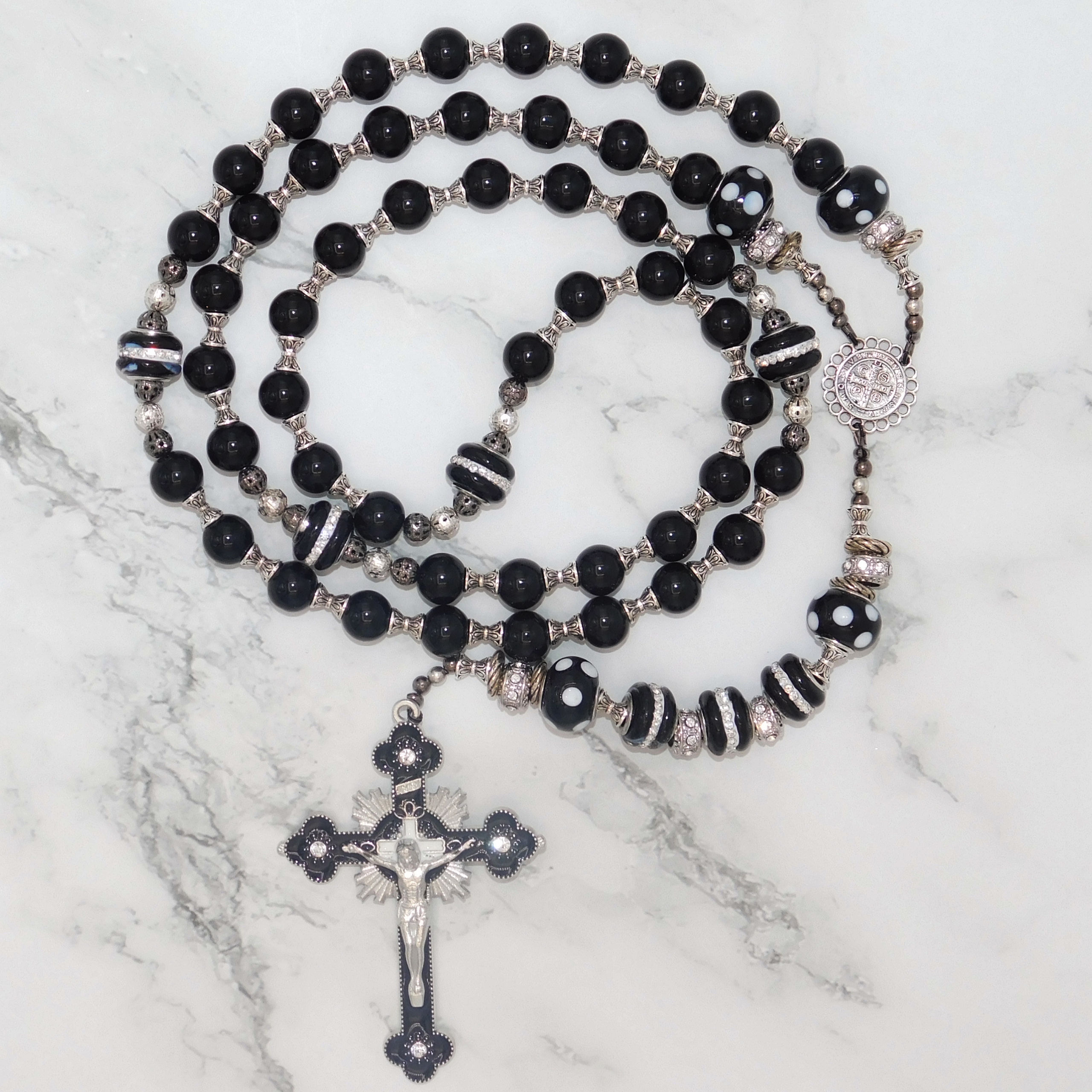"Elegant black onyx rosary with silver crucifix, featuring intricate beadwork and a Benedictine medal