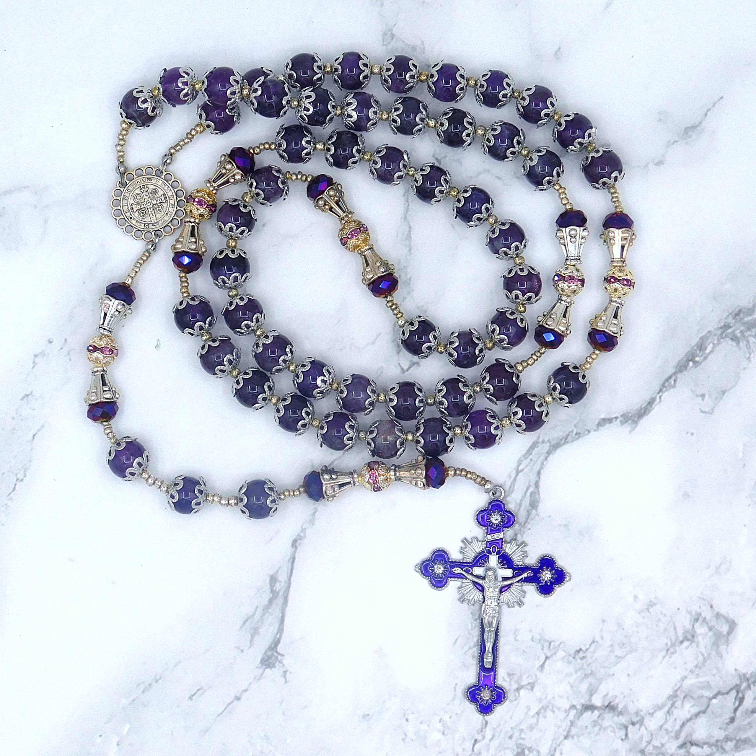 Elegant handmade amethyst rosary with silver accents, intricate beadwork, & a detailed purple crucifix, displayed on marble