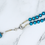Thumbnail: A beautifully designed turquoise and silver rosary with ornate beads and crystal accents is displayed on white marble
