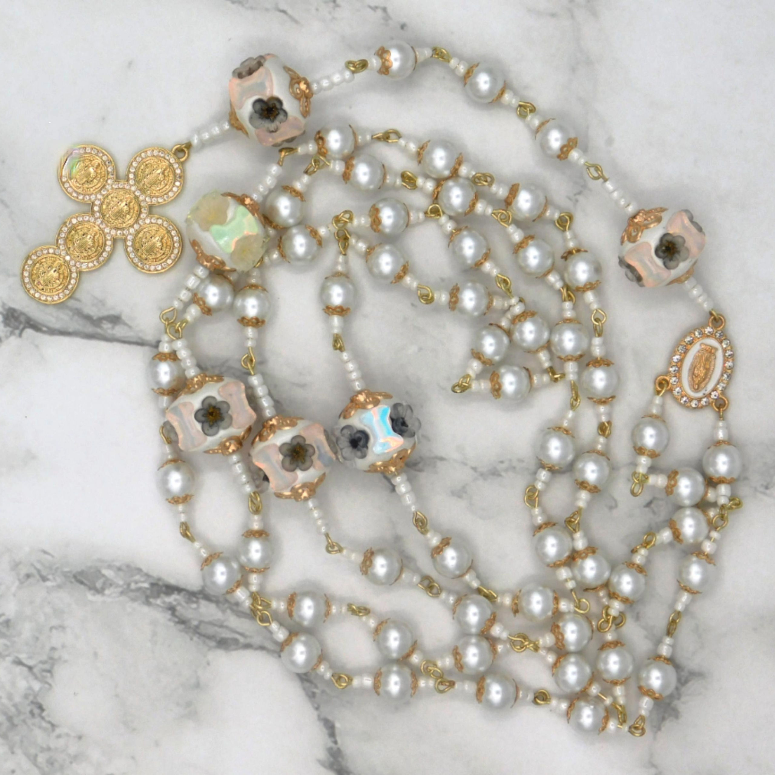 Elegant Catholic rosary with white pearl beads, gold accents, floral ceramic Our Father beads, and a decorative gold crucifix