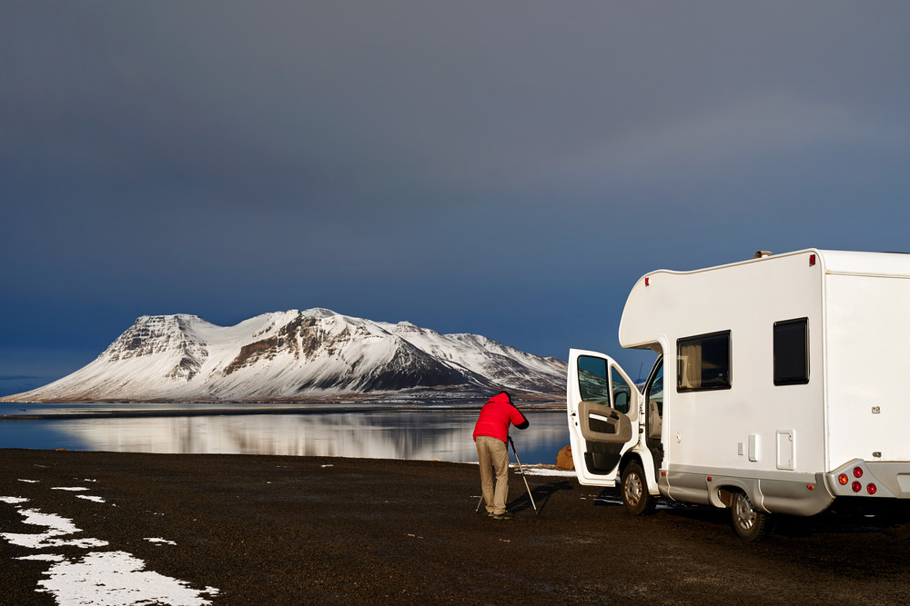Fotógrafo al lado de una Autocaravana en paisaje nevado en Islandia.