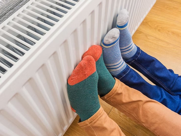 children warming up their feet in the radiator