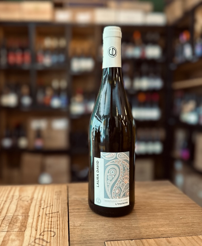 bouteille de vin blanc l'Insolente de la vigneronne Laura David dans la vallée de la Loire présentée debout devant une étagère remplie de bouteilles