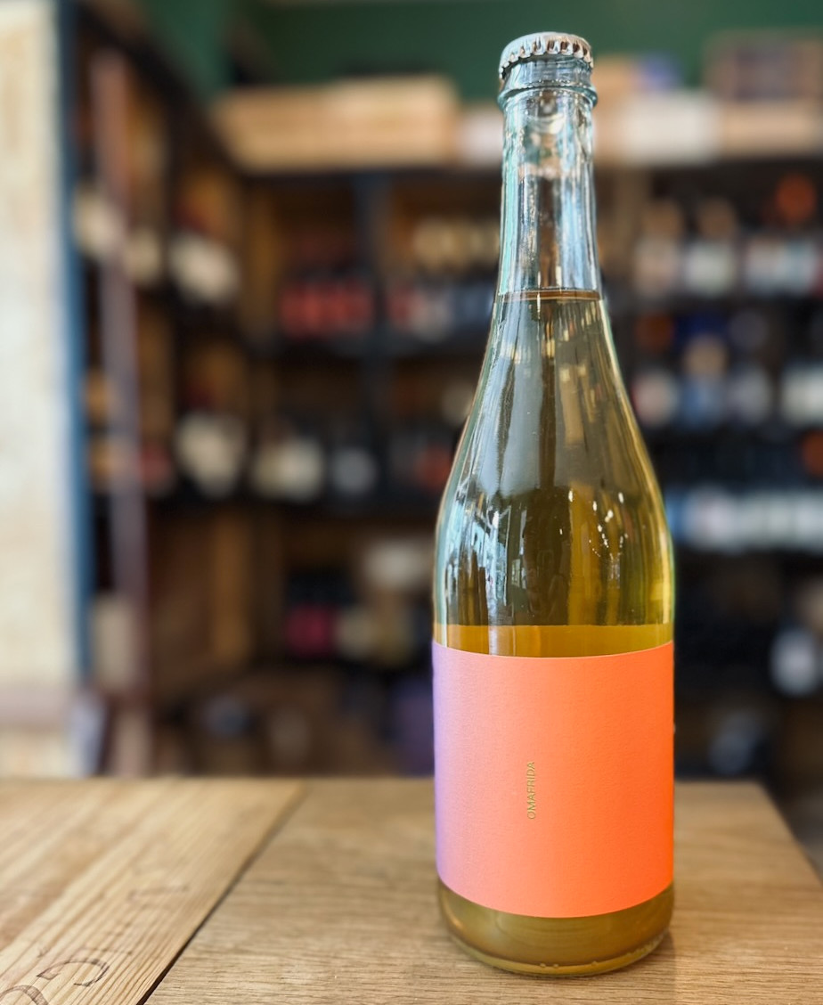 bouteille de boisson sans alcool à base de jus de raisin de la marque Omafrida posée sur une table devant une étagère de bouteilles de vins