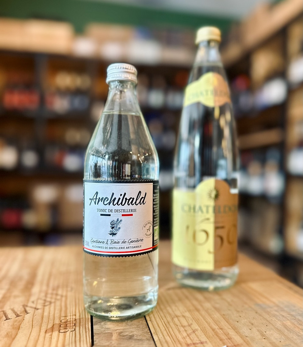 bouteille de boisson sans alcool tonic Archibald et eau pétillante Chateldon posée sur une table devant une étagère de bouteilles de vins