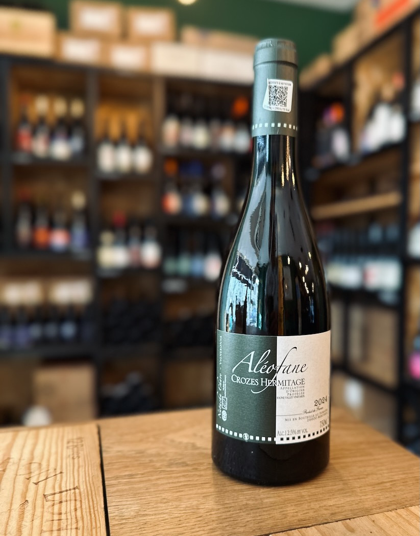 bouteille de vin blanc du domaine Aléofane en Crozes-Hermitage en Rhône nord présentée debout devant une étagère remplie de bouteilles