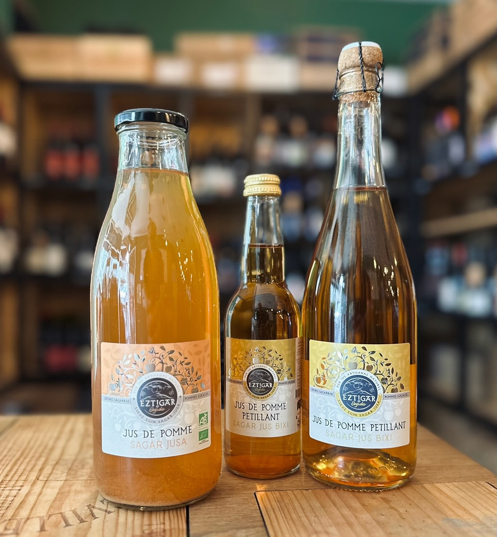 bouteille de boisson sans alcool à base de jus de pomme de la marque Eztigar posée sur une table devant une étagère de bouteilles de vins