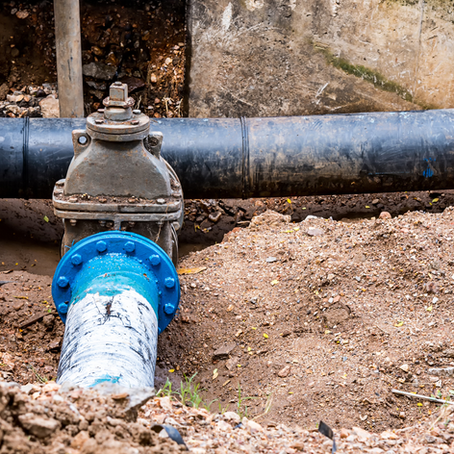 Old underground water pipes with a rusted valve exposed during excavation.