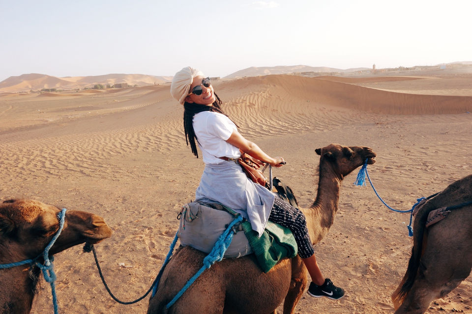 Solo traveler riding a camel through the Sahara Desert dunes in Morocco