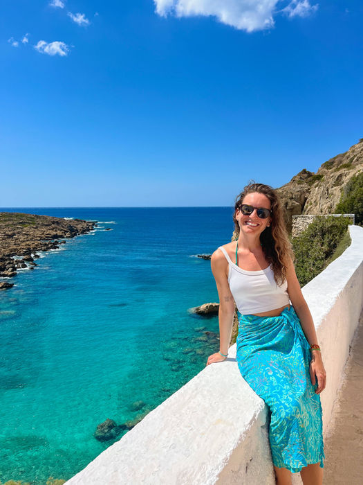 solo female traveler relaxing on a the gorgeous coastline of Crete, Greece