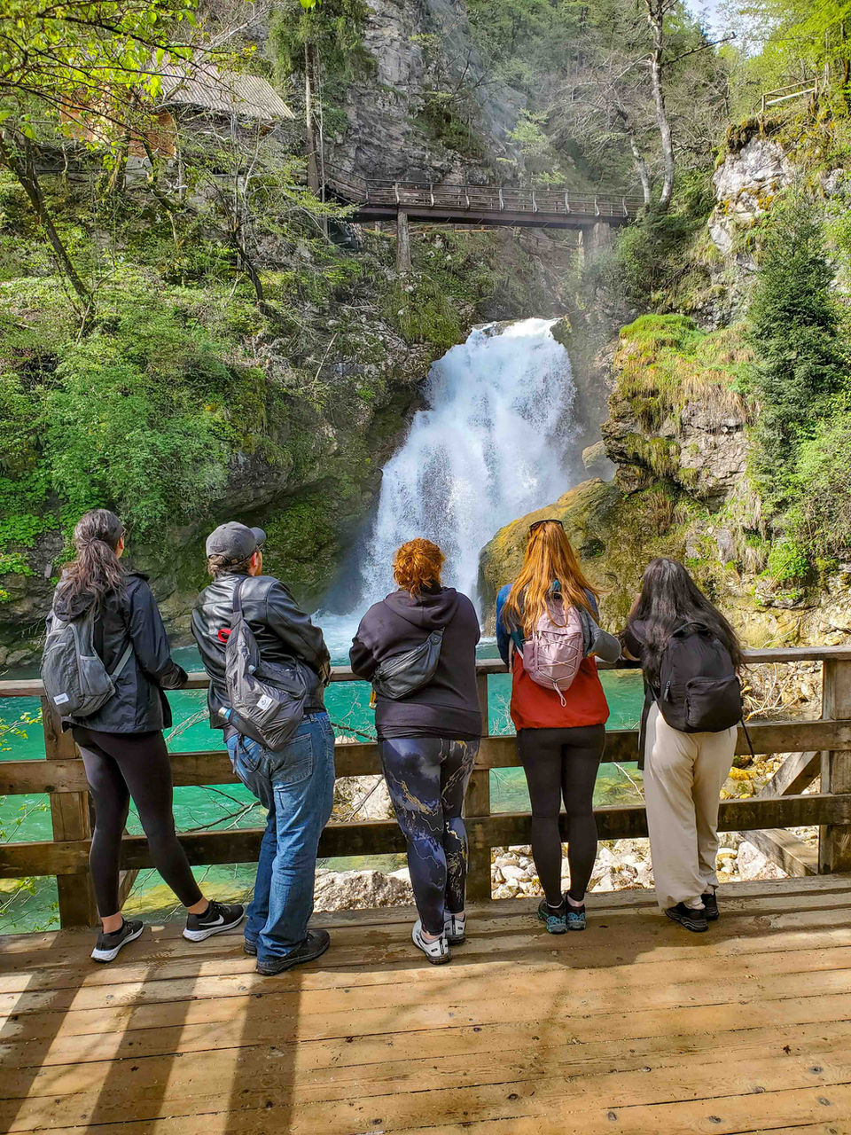 Young travelers posing in front of a waterfall in Slovenia.