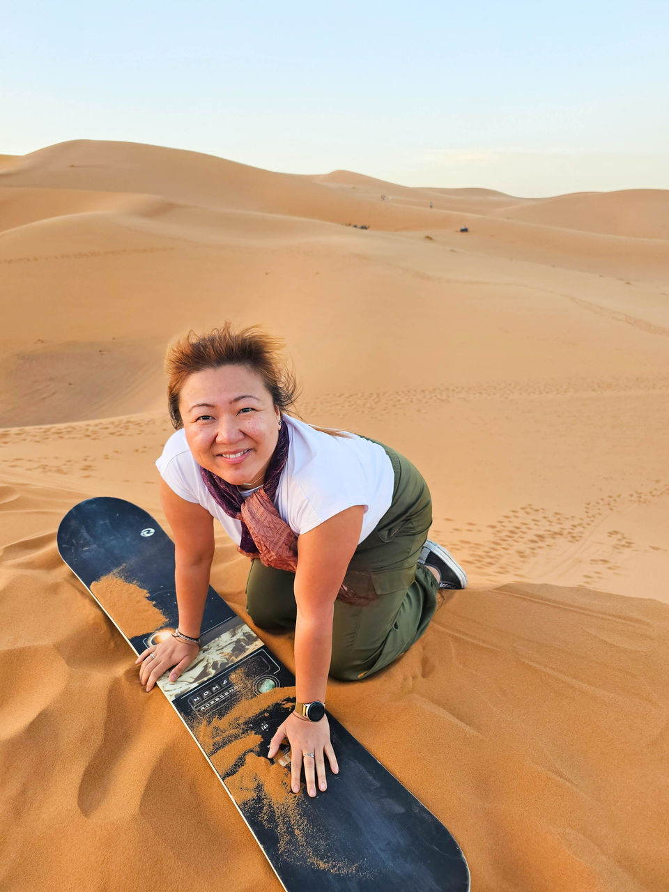solo traveler sandboarding down the dunes in the Sahara Desert
