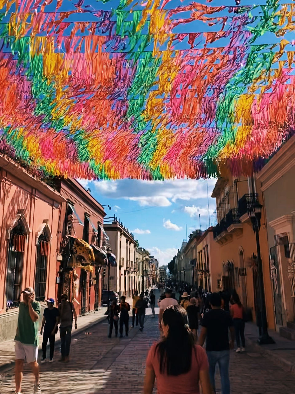 Colorful papel picado decorations hanging above a busy street in Oaxaca City