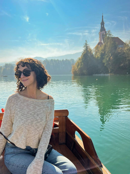 A young female solo traveler sitting on a boat on Lake Bled