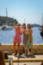 Solo travelers enjoying drinks by the harbor in the South of France with yachts in the background