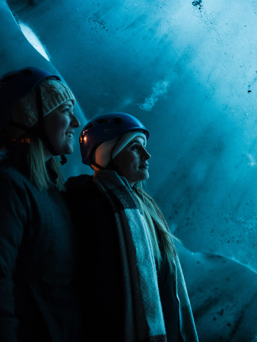 young travelers inside a glowing blue ice cave in Iceland