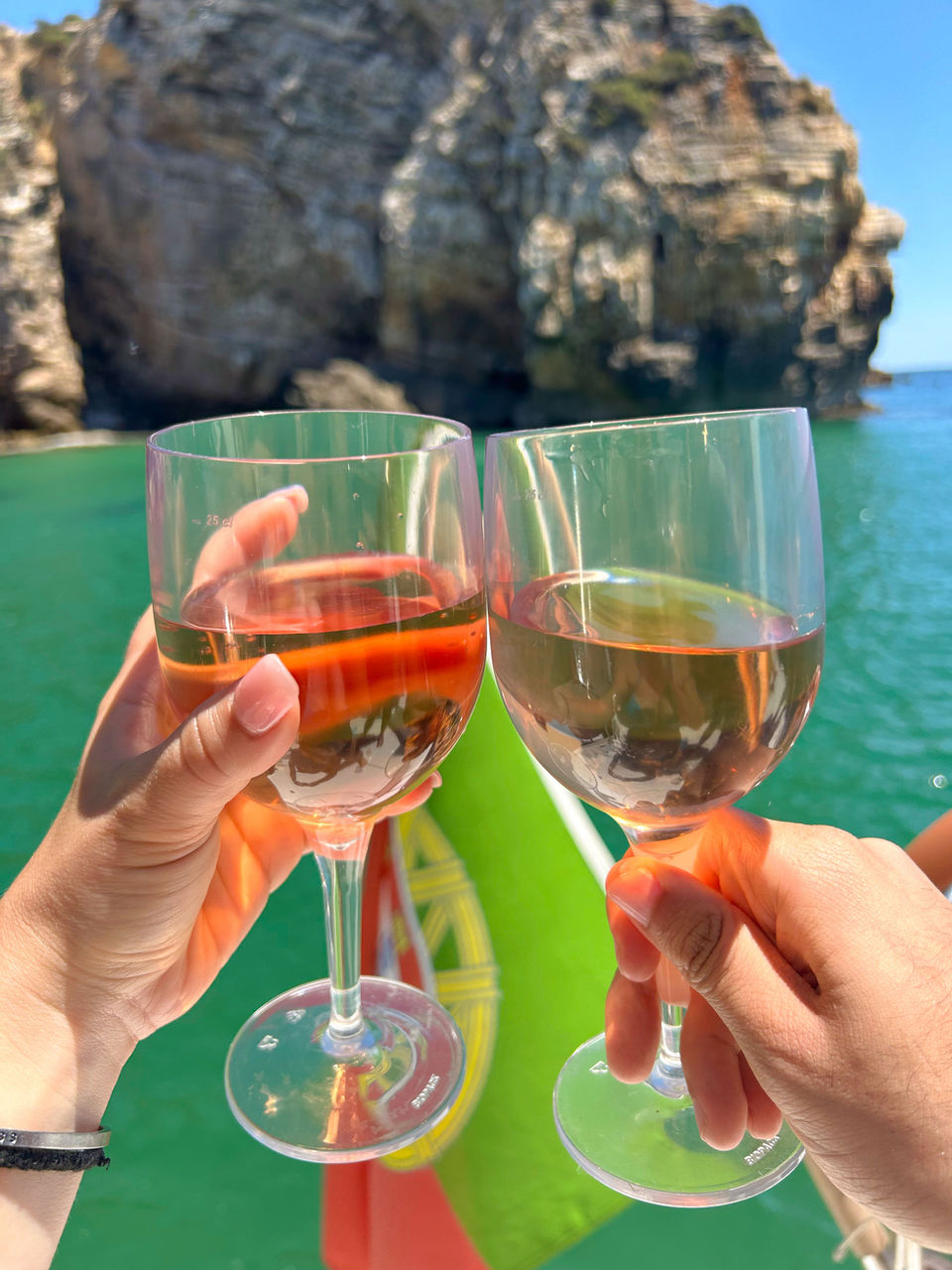 two hands holding glasses of wine on a boat in Lagos, Portugal