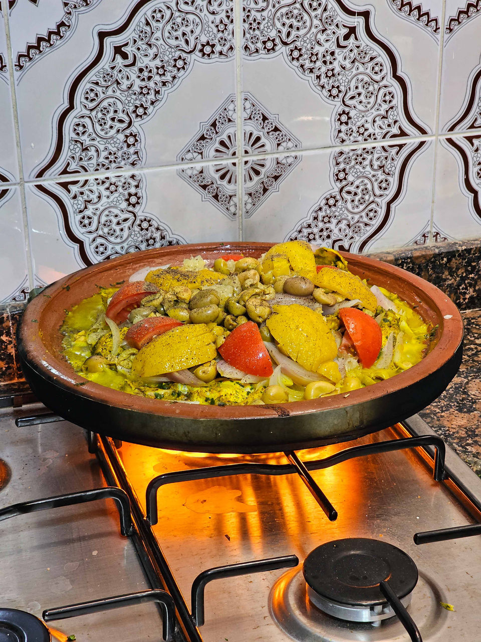 Colorful Moroccan tagine with vegetables and chicken cooking on a stove