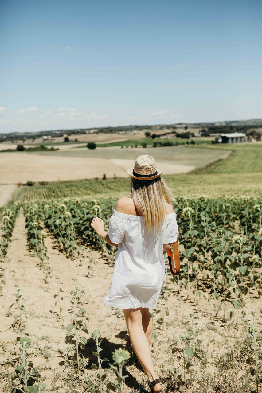 solo traveler walking through vineyards in Tuscany on a sunny day