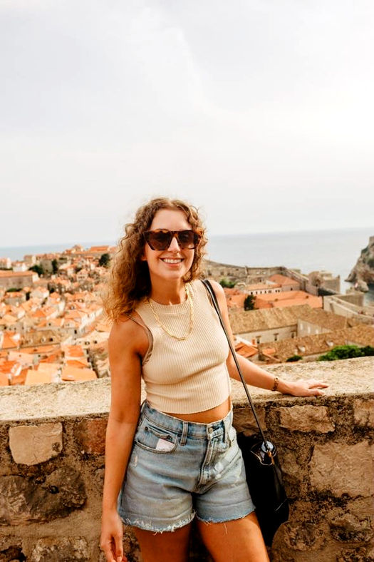 Solo traveler smiling with views of Dubrovnik’s terracotta rooftops