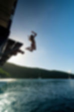 Guest jumping off Willy T floating bar in the BVI, private boat charter adventure