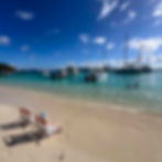A day trip to White Bay Jost Van Dyke with turquoise water, anchored boats, and beach chairs showing what visiting St. John USVI by Season looks like at its most beautiful