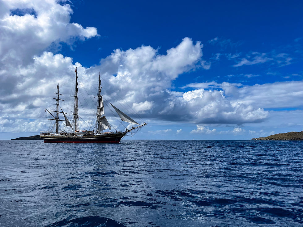 Three-masted sailing ship crossing deep sapphire-blue water in the British Virgin Islands.