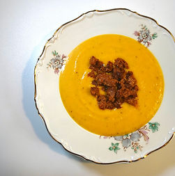 Bright roasted pumpkin soup topped with a generous mound of crispy chorizo in an elegant bowl.