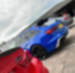 Three luxury cars parked: red BMW, blue Audi RS6, gray Mercedes