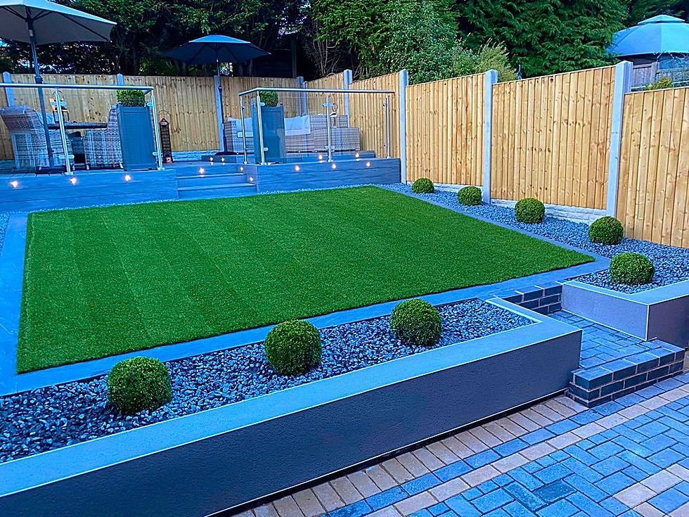 Landscaped garden with artificial grass lawn, grey paving, spherical topiary shrubs.