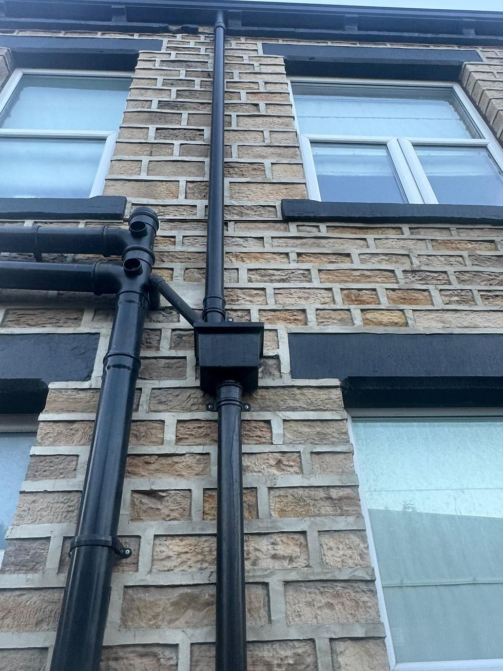 Exterior brick wall with black pipes and gutters