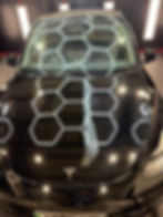 Black Tesla car reflecting hexagonal lights, showcasing Ceramic Coating Cheshire.