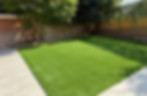 Green lawn with a fence and trees Kt-Landscaping in the background.