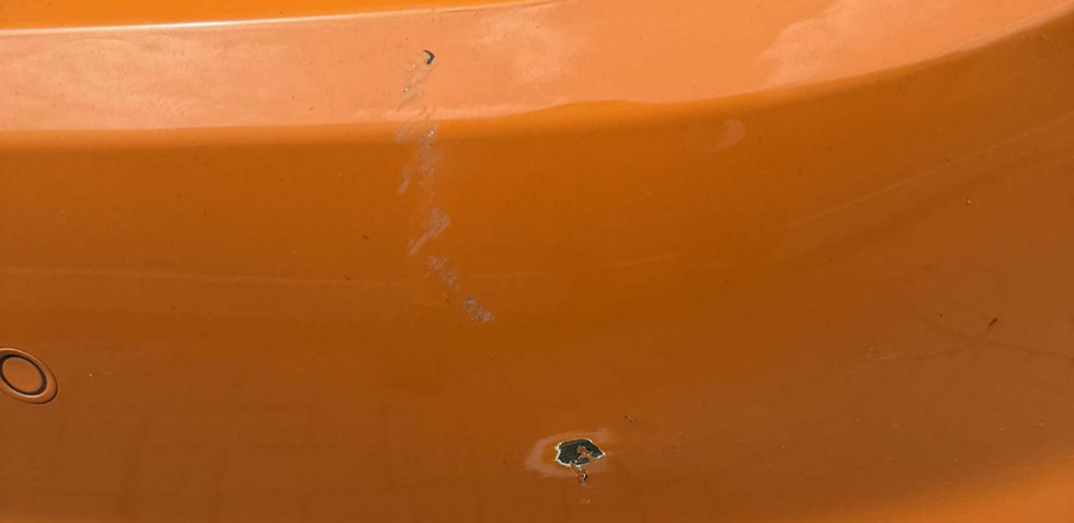 Orange car bumper with scratches and damage
