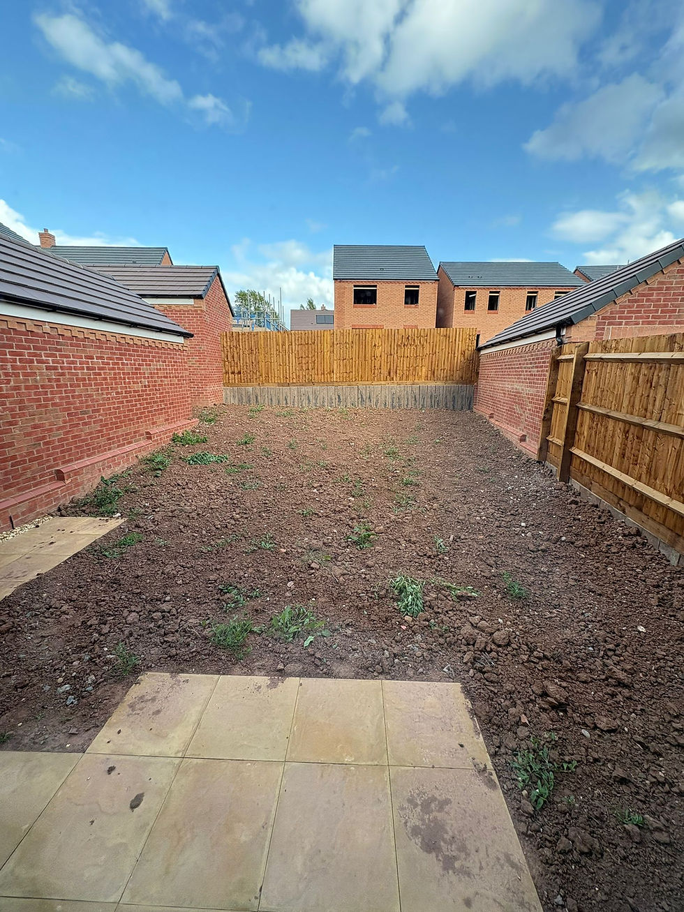 Residential backyard with bare soil, fences, and brick walls under blue sky Kt-Landscaping